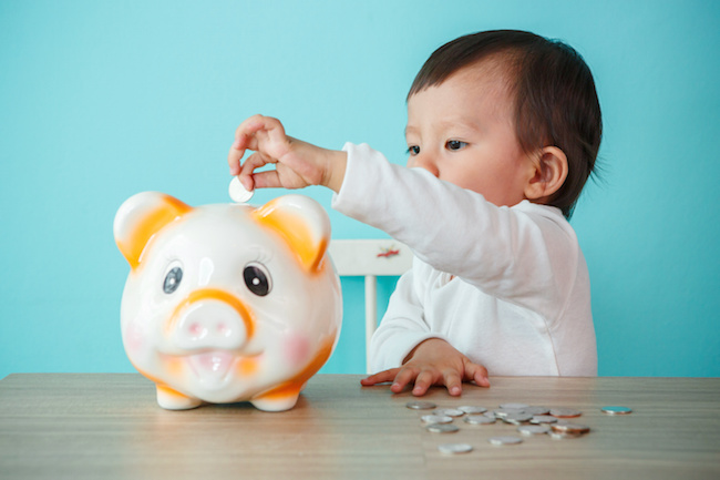 little baby moneybox putting a coin into a piggy bank - kid saving money